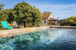 A clear swimming pool with lounge chairs, a gazebo, and a building with a tiled roof. - Villa les Rocs (La Bachellerie)