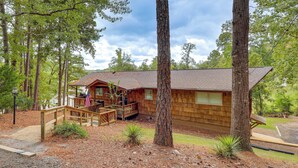 A cabin with a wooden exterior, a deck, and a view of the surrounding forest. - Beautiful Lakefront Home with Plenty of Space! (Jacksons' Gap)