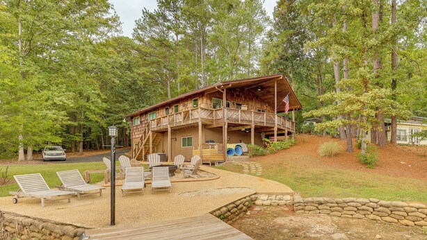 A cabin with a deck, outdoor seating, and a stone wall. - Beautiful Lakefront Home with Plenty of Space! (Jacksons' Gap)