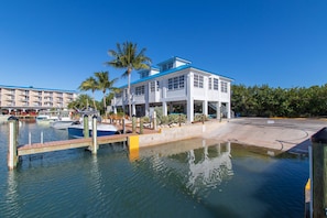 A waterfront hotel with a dock, boats, and a clear blue sky.
