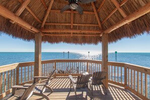 A wooden deck with chairs and a thatched roof, overlooking the sea. - Island Getaway at Ocean Point (Tavernier)