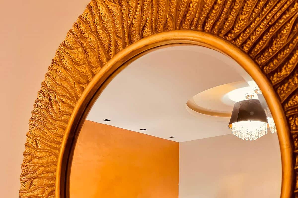A room with a large mirror, a bed, and a lamp.
