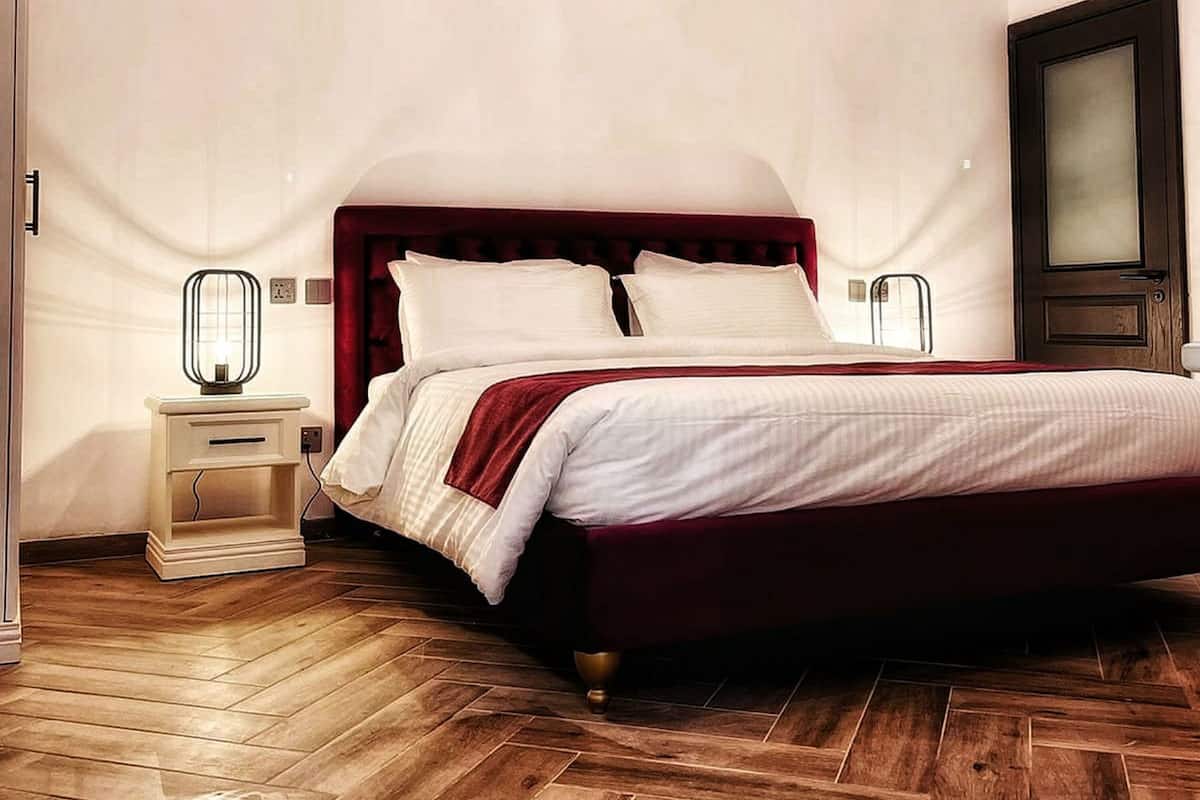 A neatly arranged bedroom with a large bed, a nightstand, and a wall-mounted TV.