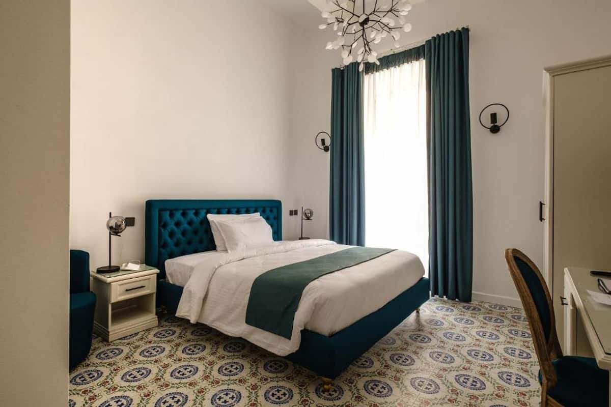 A neatly arranged bedroom with a bed, bedside table, lamp, and a chair.