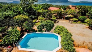 A swimming pool surrounded by lush greenery and a view of the sea.