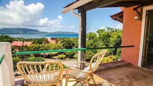 A balcony with wicker chairs and a view of a coastal landscape.