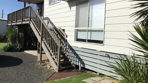 A two-story house with a wooden staircase leading to a balcony. - Bay Views Beach Surfing Fishing Boating (Surf Beach)