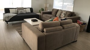 A modern living room with two sofas, a coffee table, and a floor lamp. - Bay Views Beach Surfing Fishing Boating (Surf Beach)