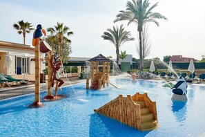 Zona de piscina con fuentes, palmeras y sillas de descanso.