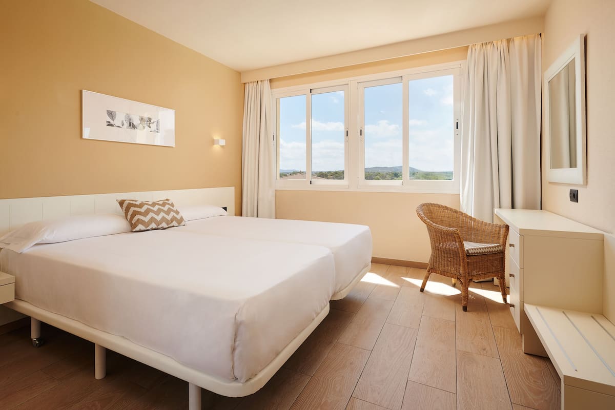 Una habitación de hotel con cama, una silla, escritorio y ventana con vistas.