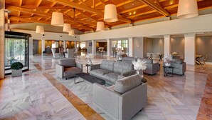 A spacious lobby with a high ceiling, large windows, and a mix of seating areas including sofas and chairs. - Protur Badí­a Park Aparthotel (Sant Llorenc des Cardassar)