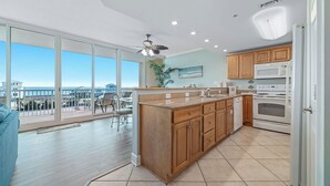 A modern kitchen with wooden cabinets, a central island, and a view to the outside.