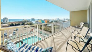 A balcony with a view of a swimming pool and beach houses.