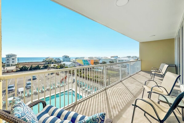 A balcony with a view of a swimming pool and beach houses.