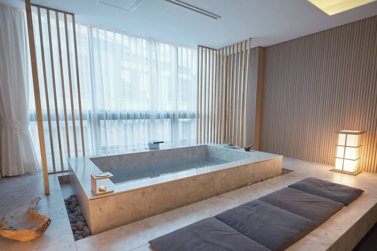A modern bathroom with a large bathtub, wooden accents, and a minimalist design.