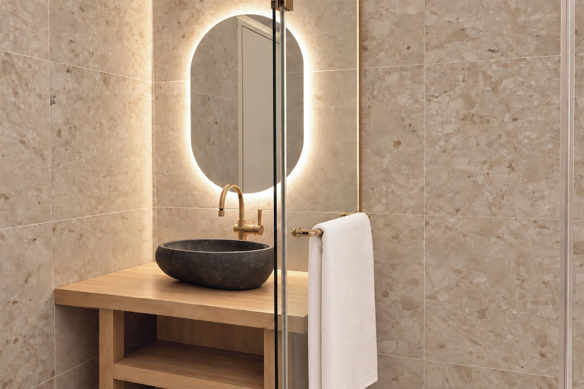 Un baño con un espejo redondo, un lavabo sobre encimera y un perchero para toallas.