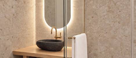 Un baño con un espejo redondo, un lavabo sobre encimera y un perchero para toallas.