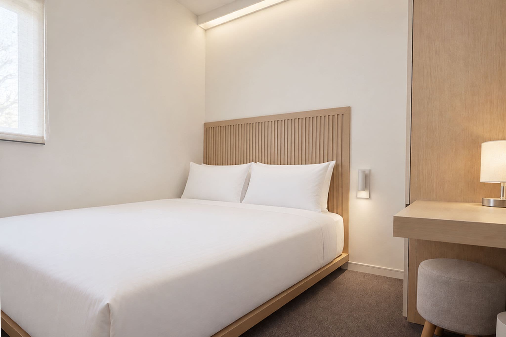 A hotel room with a bed, a desk, and a chair.