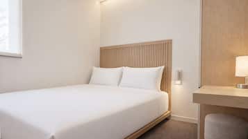 A hotel room with a bed, a desk, and a chair.