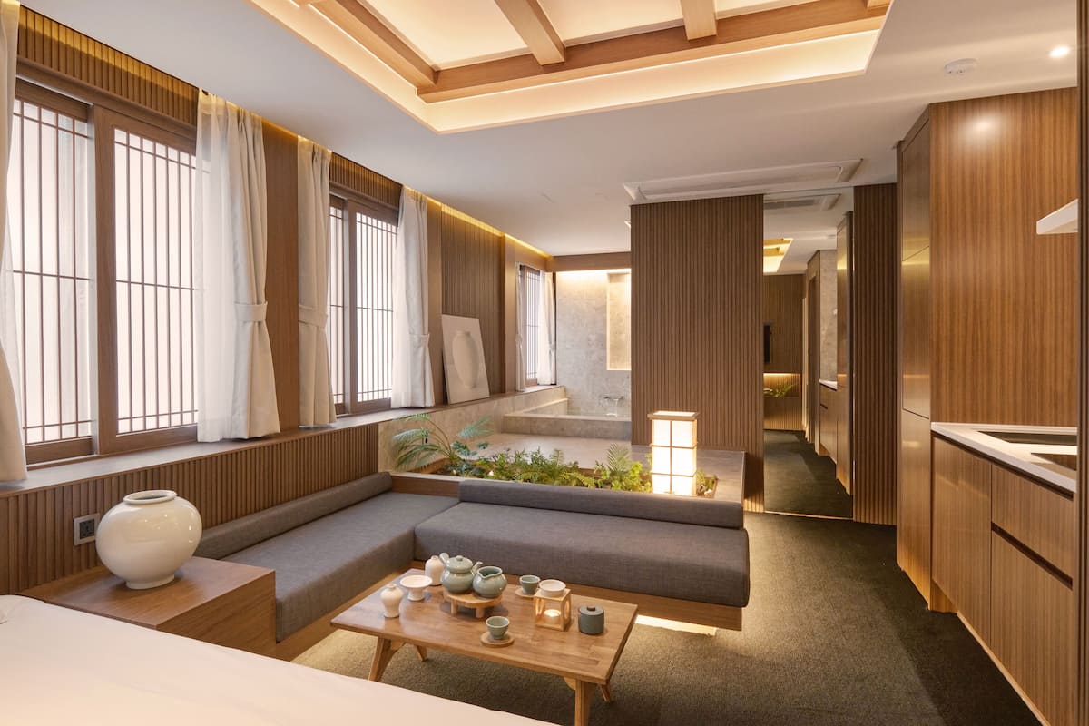 A modern interior with a sofa, a coffee table with tea sets, and a view of a hallway.