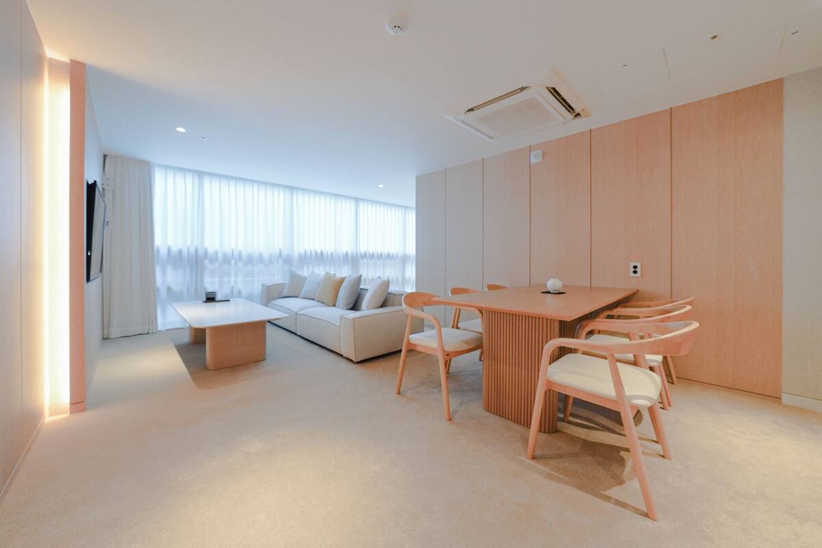 A modern living room with a sofa, a coffee table, and a dining table with chairs.