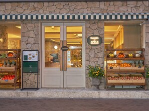 A storefront with a stone facade, a sign reading "Sounds of Apple," and displays of fruits and vegetables. - UH Suite The Myeongdong (Seoul)