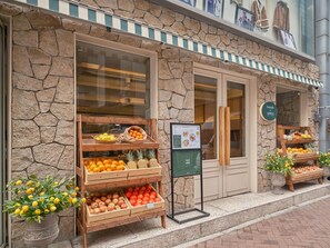A stone building with a fruit stand outside displaying oranges, apples, and lemons. - UH Suite The Myeongdong (Seoul)