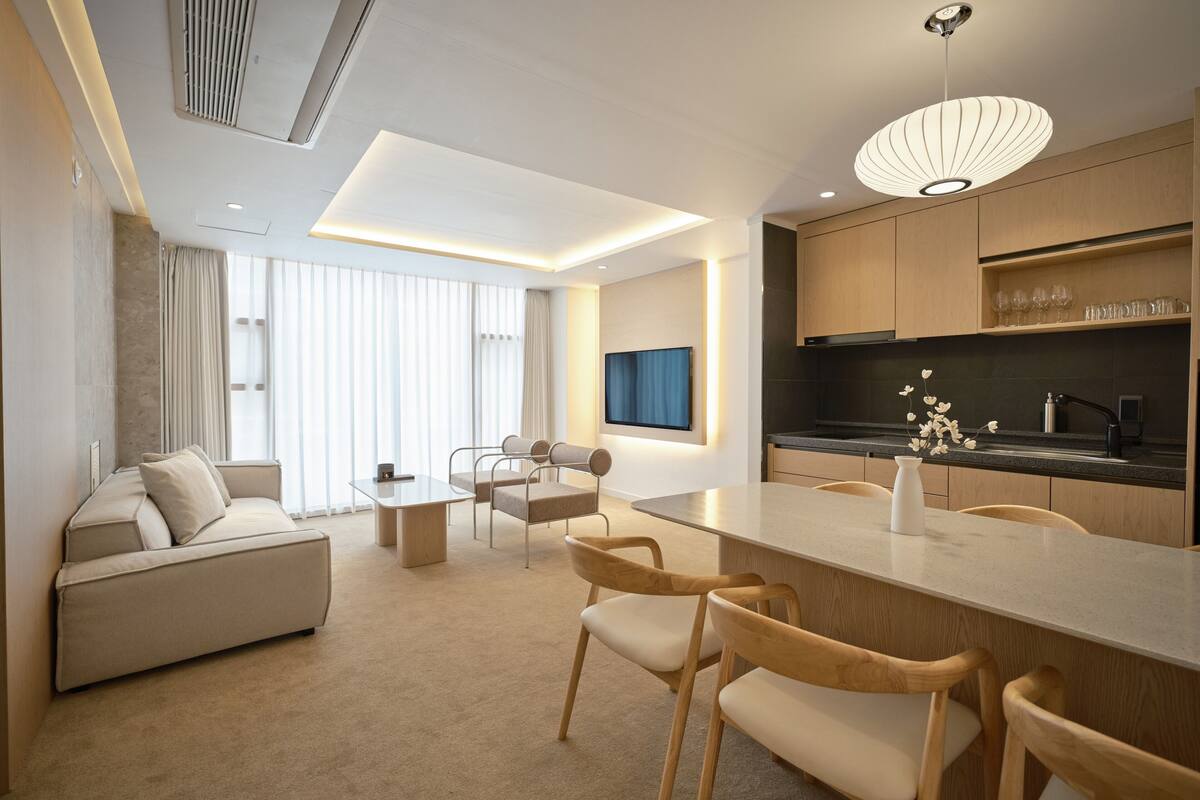 A modern hotel room with a living area, a dining space, and a kitchen.