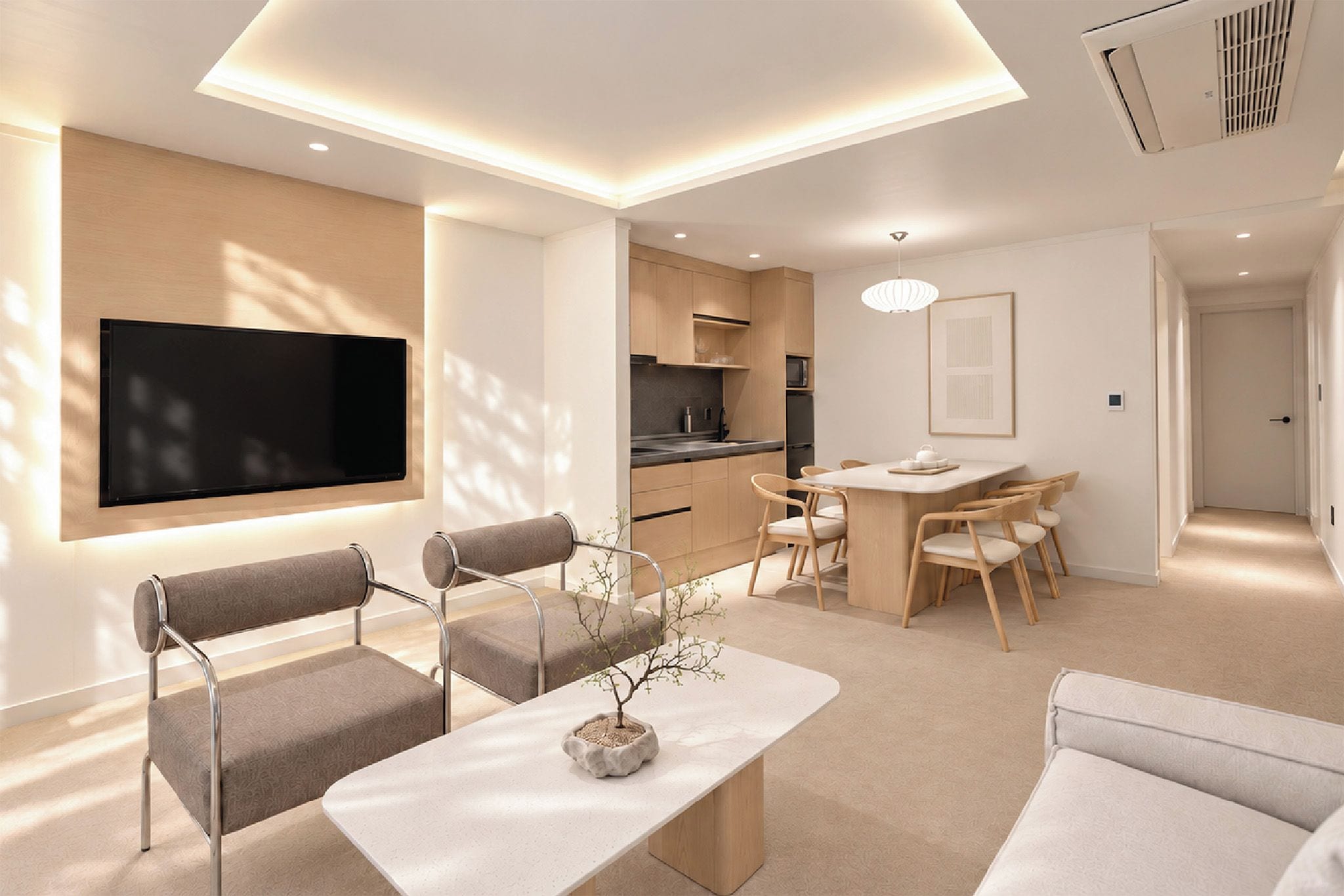 A modern living room with a flat-screen TV, a dining area with a table and chairs, and a kitchen in the background.