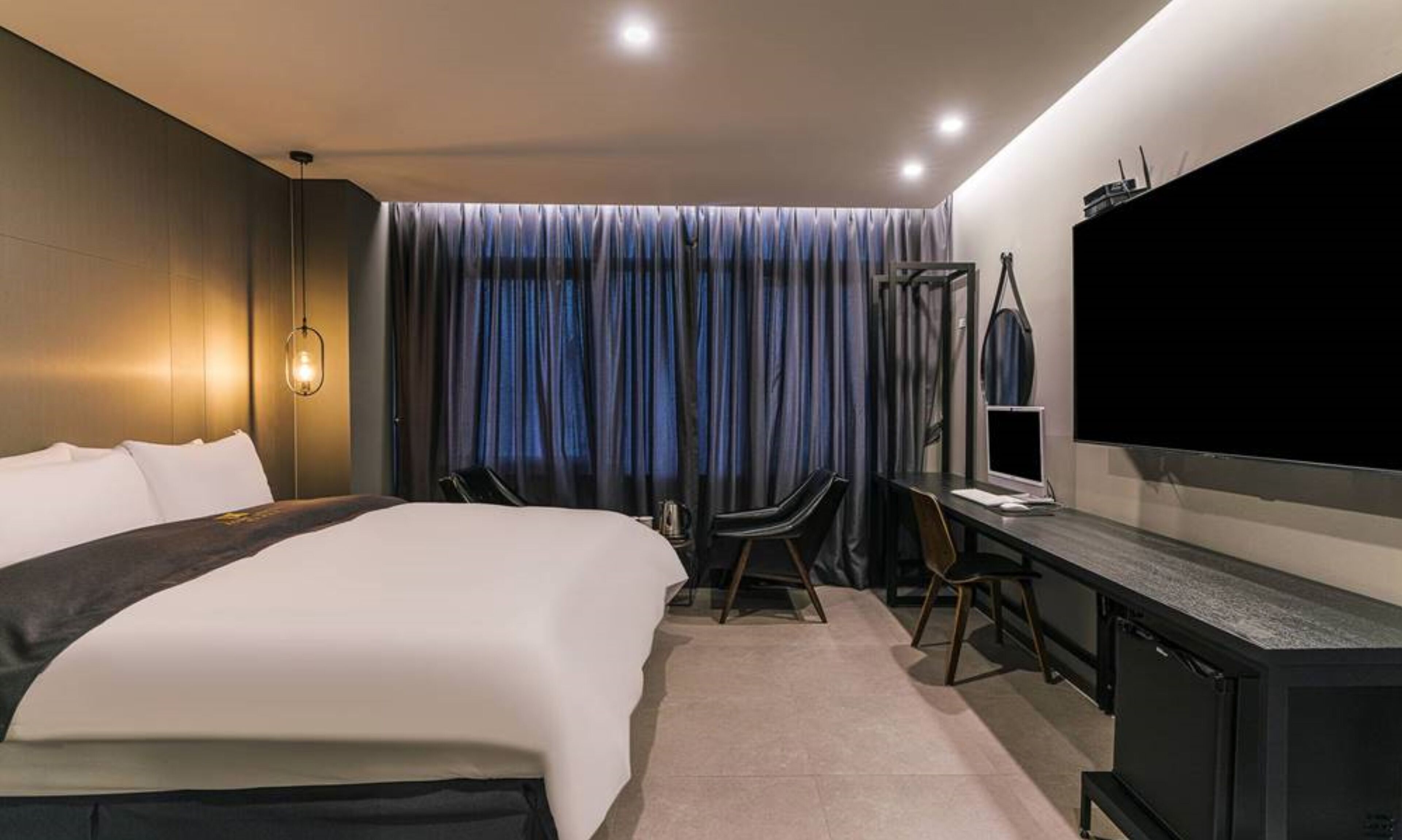 Een moderne hotelkamer met een groot bed, een bureau met een computer en een televisie.