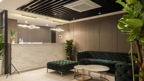A modern reception area with a marble counter, green upholstered seating, and a minimalist design. - Namyangju Aone Hotel (Namyangju)