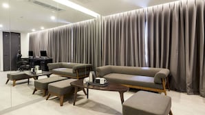 A modern living room with a sofa, two armchairs, and a coffee table. There is a desk with a computer and a chair. The room has large curtains and a mirror on the wall. - Namyangju Aone Hotel (Namyangju)