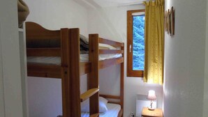 A small, compact room with bunk beds and a window with curtains. - Cozy apartment in Valfréjus, near lifts (Modane)