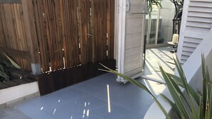 Ein gepflasterter Patio-Bereich mit Fischgrätmuster, ein Holzzaun und ein Blumentopf.