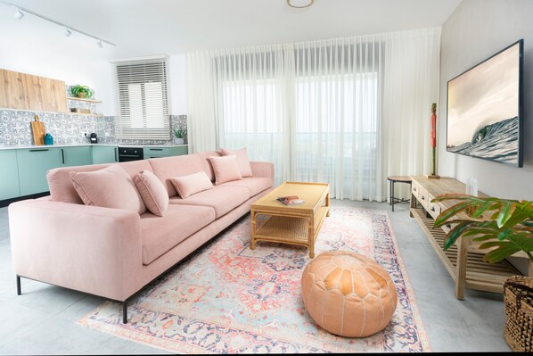 A modern living room with a pink sofa, a wooden coffee table, and a patterned rug.