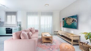Una sala de estar moderna con un sofá rosa, una mesa de centro de madera y una alfombra colorida.