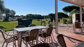 An outdoor patio area with a table and chairs, a grill, and a view of a green landscape. - IN THE QUIET AREA OF NOVO SANCTI PETRI (Chiclana de la Frontera)