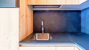 Una cocina moderna con armarios de madera, un lavamanos de acero inoxidable y una encimera oscura.