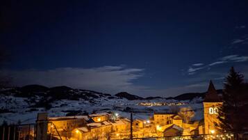A snow-covered village at night with illuminated buildings and a church tower.