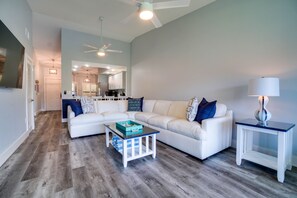 A modern living room with a white sectional sofa, a coffee table, and a side table with a lamp.