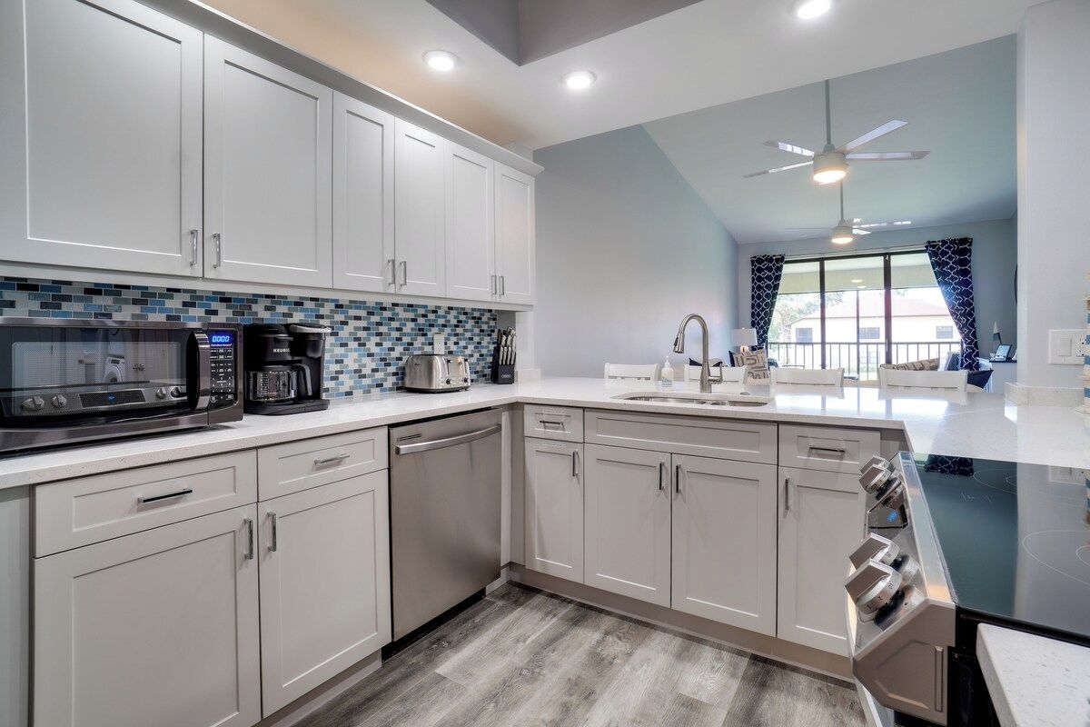 A modern kitchen with white cabinets, a microwave, coffee maker, and a dishwasher.