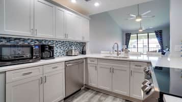 A modern kitchen with white cabinets, a microwave, coffee maker, and a dishwasher.