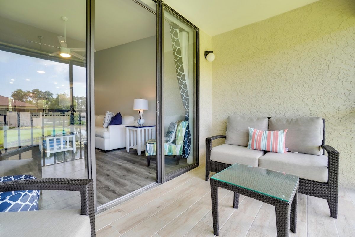 A balcony with wicker furniture, a glass table, and a view of the outdoor area.