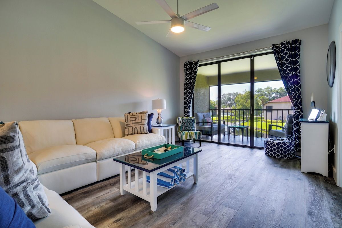 A modern living room with a sofa, coffee table, and a view through large sliding glass doors to an outdoor area.