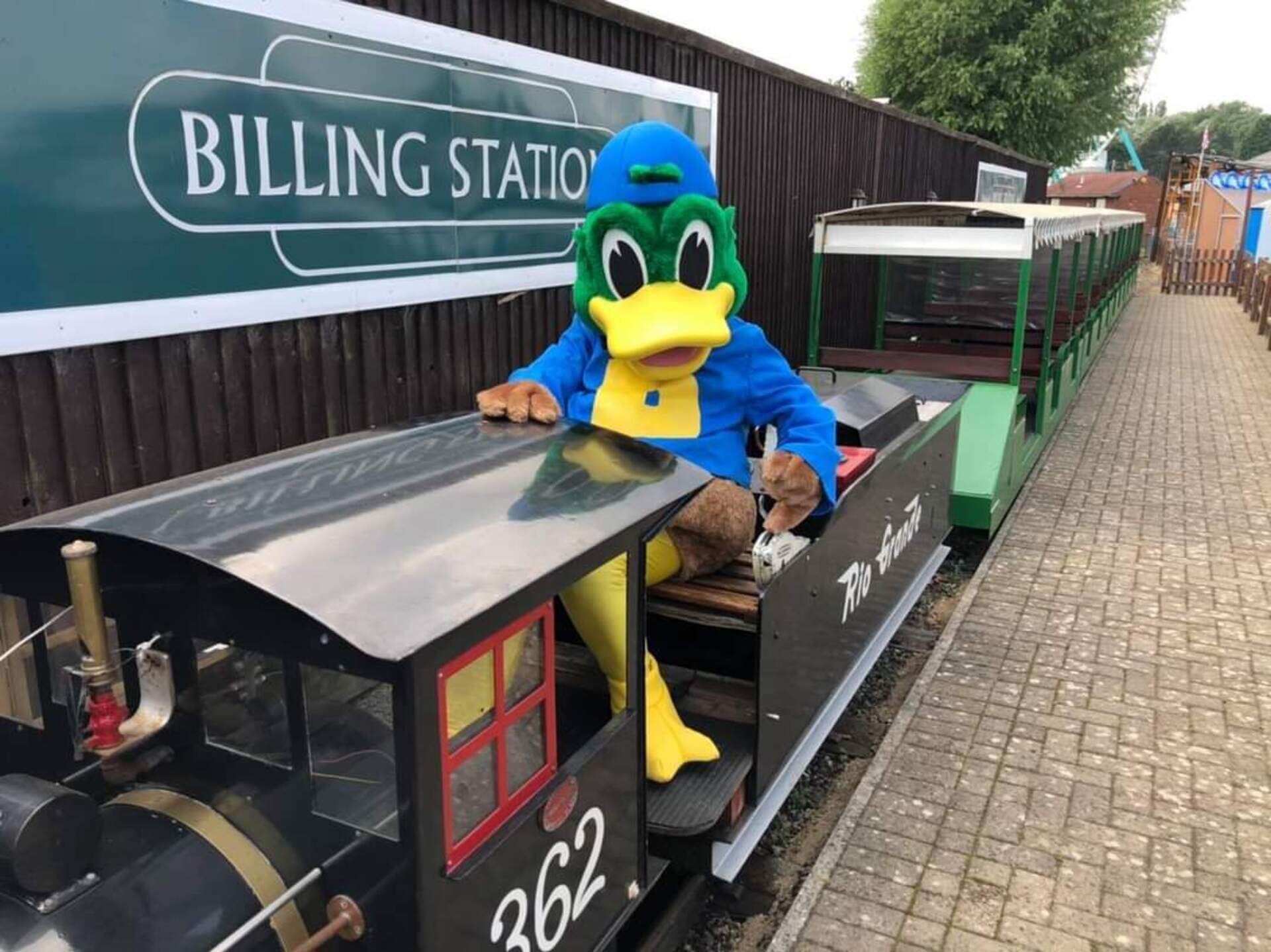 Un pato, mascota, sobre un tren en miniatura en una estación temática llamada BILLING STATION.