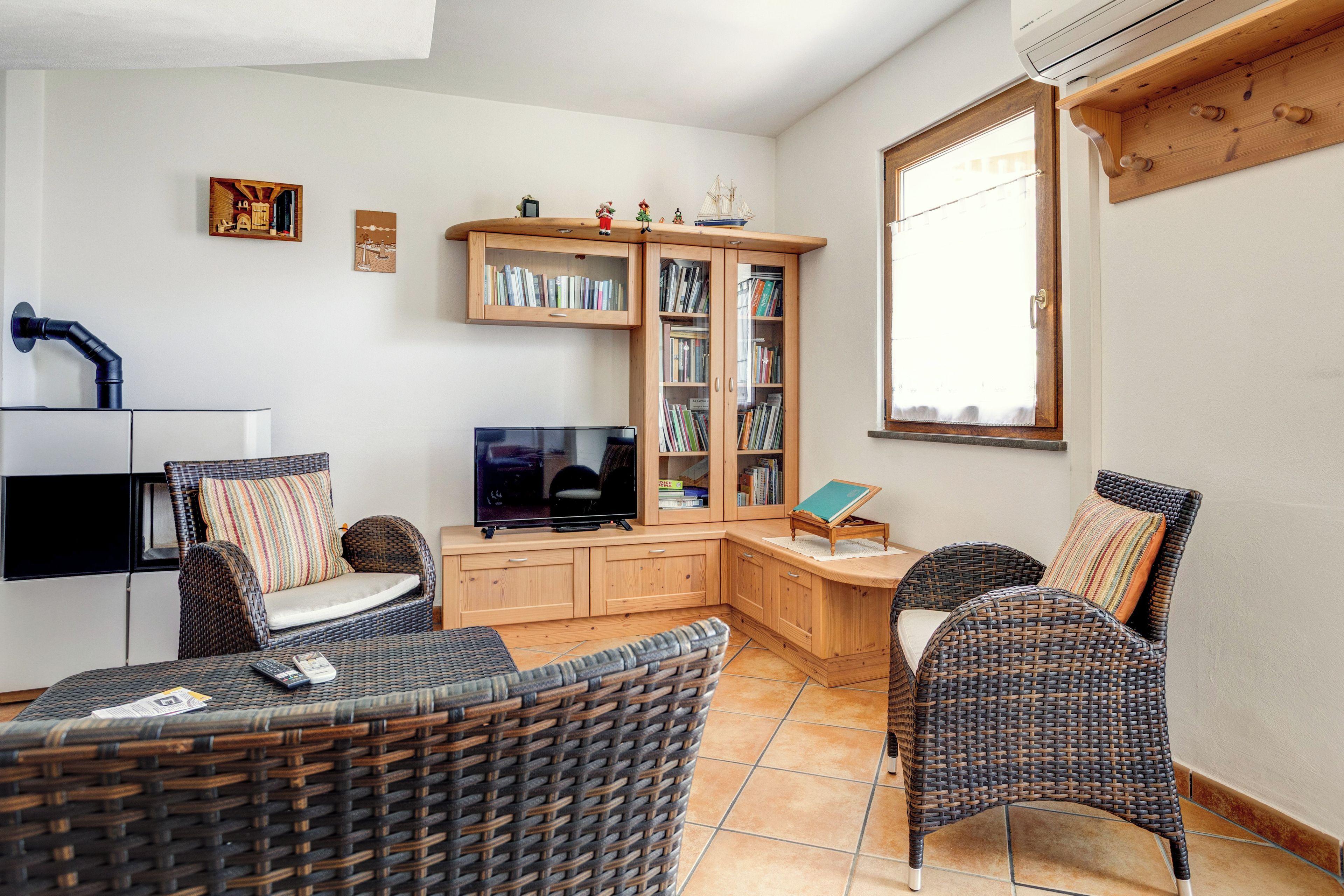 A cozy living area with wicker furniture, a flat-screen TV, and built-in bookshelves.