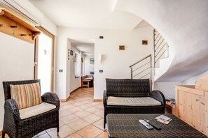 A room with wicker furniture, a staircase, and a view of a bedroom.