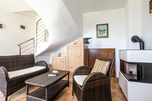 A modern living room with wicker furniture, a fireplace, and a staircase.