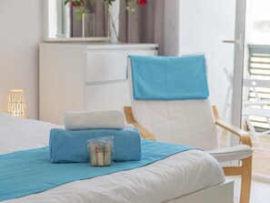 Una cama bien hecha con una toalla azul y blanca, un vaso de agua y una silla con una toalla azul.