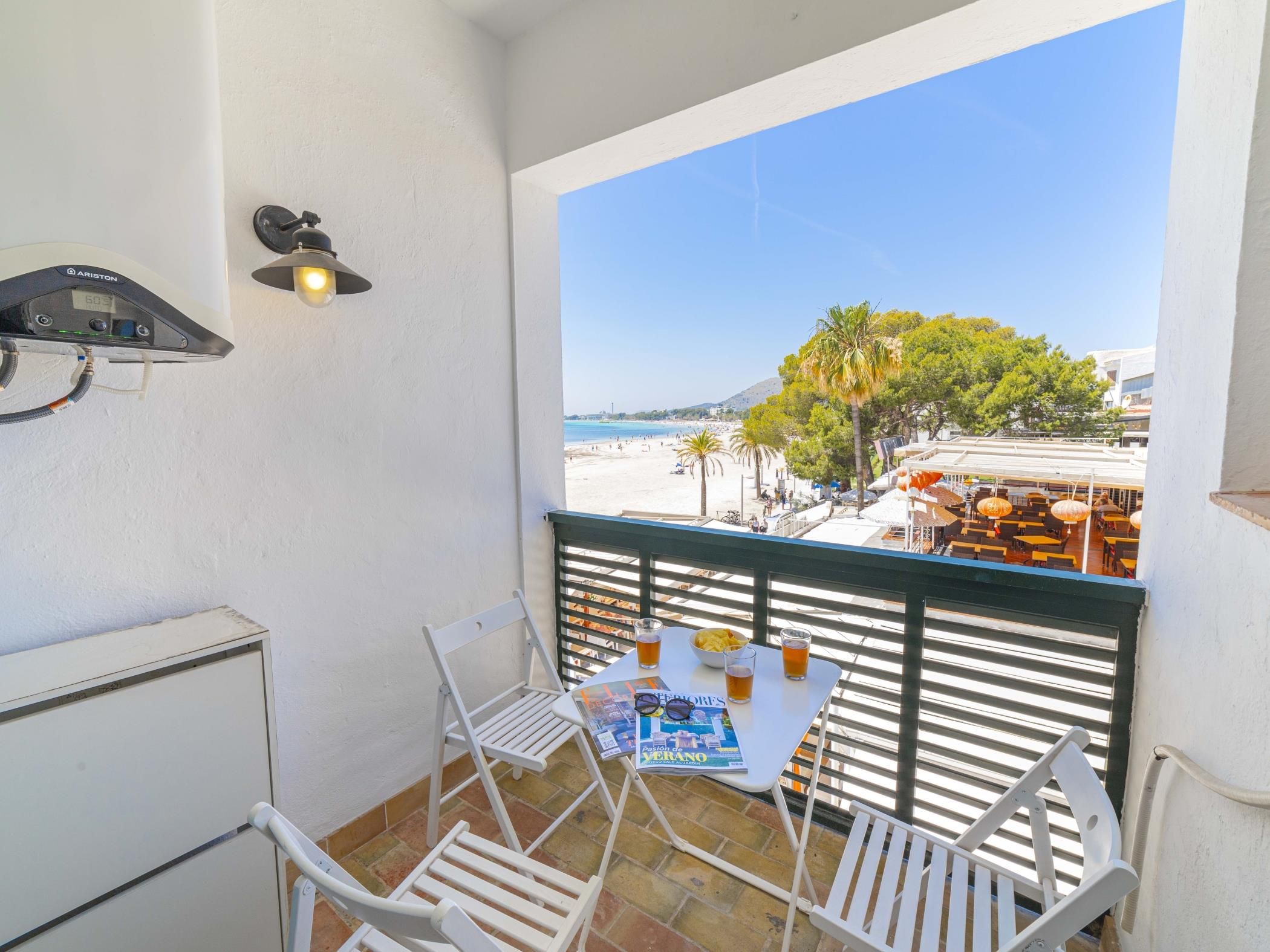 Een balkon met een tafel, stoelen, een tijdschrift en een drankje.